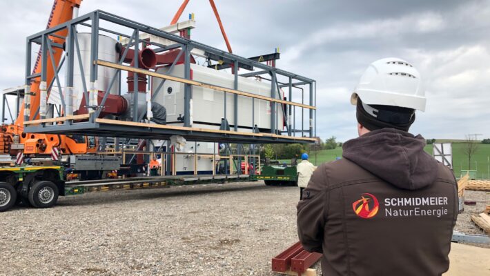 Mitarbeiter der Schmidmeier NaturEnergie (Rücken zur Kamera) beobachten Vorgang auf Baustelle