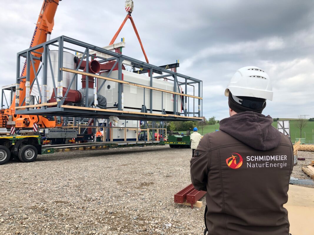 Mitarbeiter der Schmidmeier NaturEnergie (Rücken zur Kamera) beobachten Vorgang auf Baustelle