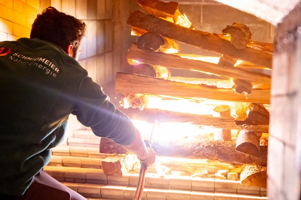 Mitarbeiter von Schmidmeier NaturEnergie entzündet mit einem Zündbrenner das Feuer in einem Biomassekessel in Feuelersdorf