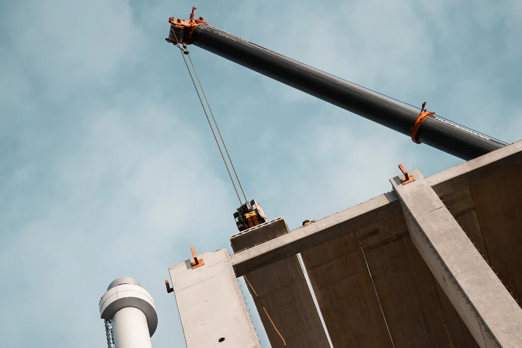 Ein Kran schließt Stück für Stück das Dach einer Biomasseanlage in Bremen. Direkt neben der Anlage ist das Ende des Schornsteins zu erkennen.