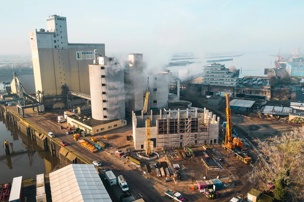 Drohnenaufnahme zeigt den Bau einer Biomasseanlage in Bremen. Die Baustelle liegt direkt am Hafen von Bremen, im Hintergrund ist die Weser zu erkennen.