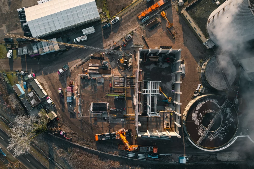 Die Baustelle einer Biomasseanlage aus der Vogelperspektive. Autos, Kräne, Container und die offene Anlage sind zu erkennen. Der Boden ist braun durch die Erde.