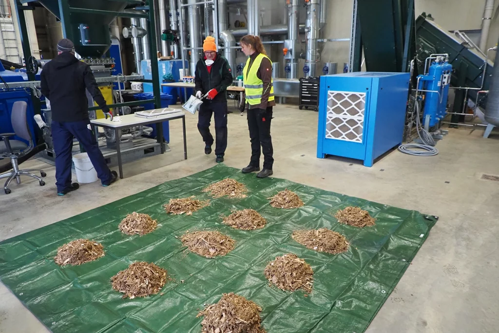 kleine Häufchen Altholz auf einer Plane verteilt