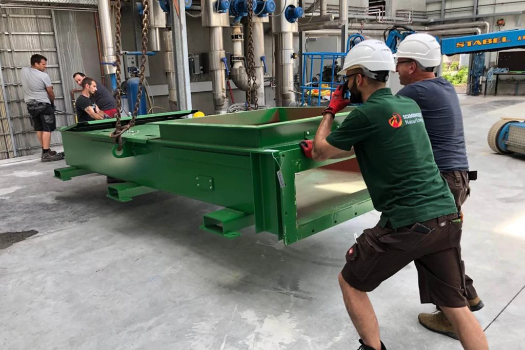 Mitarbeiter heben Komponenten der Anlage ein