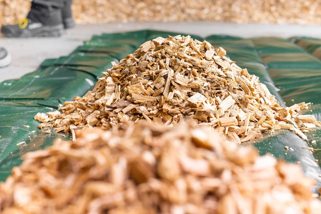 kleine Haufen mit Hackschnitzeln auf einer grünen Plane