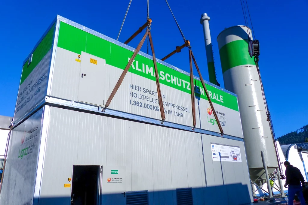 Biomasse-Dampfanlage in Baiersbronn. Zwei graue Komponenten liegen übereinander, an der Seite ragt ein Kamin nach oben. Und daneben steht ein Kessel.