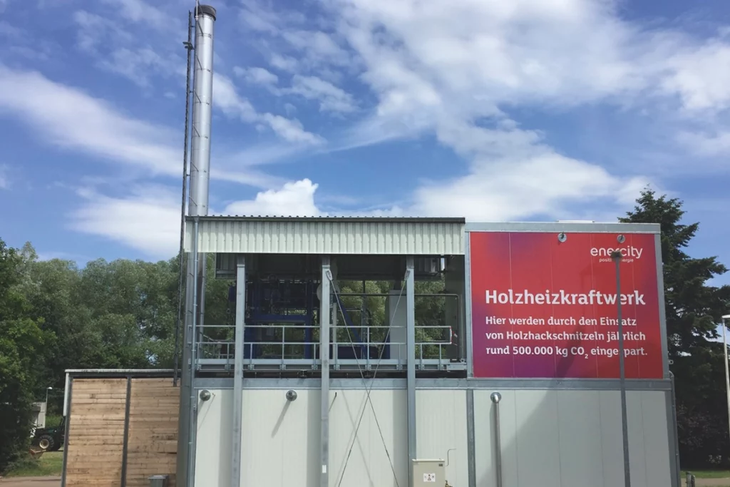 Biomassebefeuerte Dampfkesselanlage in Fuhrberg. Im Hintergrund stehen Bäume.