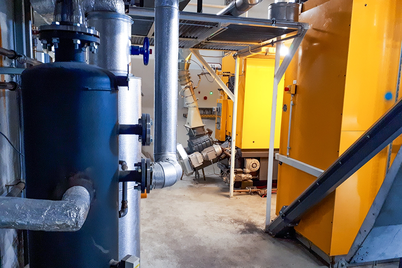 Biomassedampfkesselanlage in Gänheim von innen. Gelbe Komponenten und Rohre.
