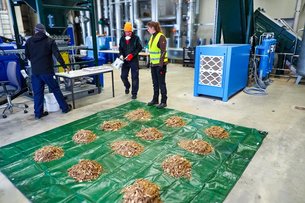 kleine Häufchen Altholz auf einer Plane verteilt