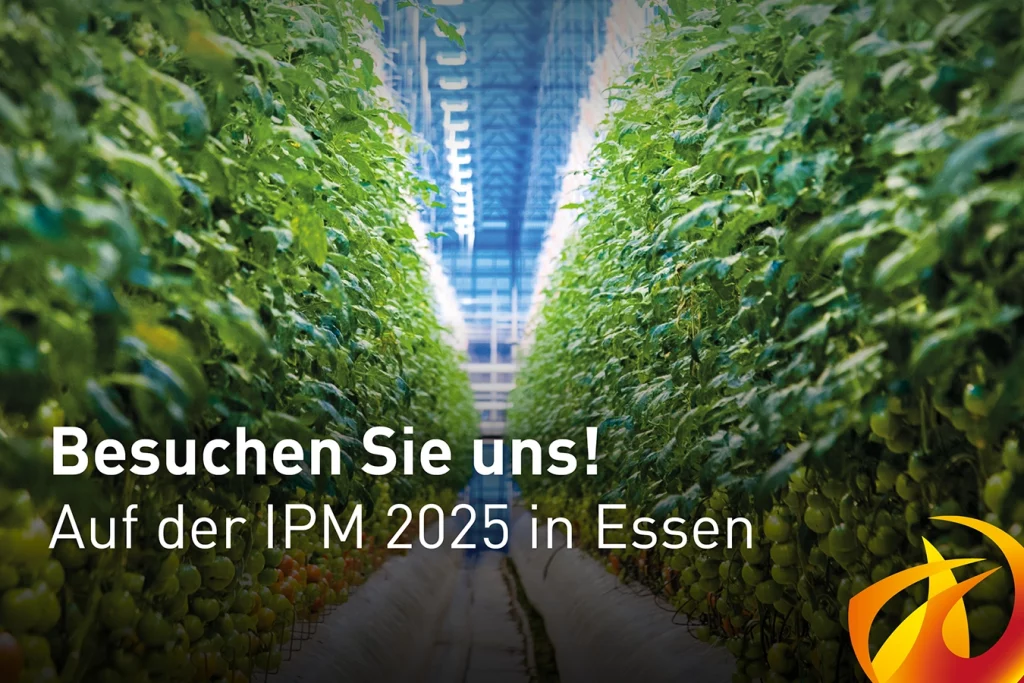 Der Text "Besuchen Sie uns! Auf der IPM 2025 in Essen" steht im Vordergrund. Dahinter ist ein Bild eines Gewächshauses zu sehen. Rechts unten befindet sich das Logo der Schmidmeier NaturEnergie GmbH, ein orange-rote Flamme.