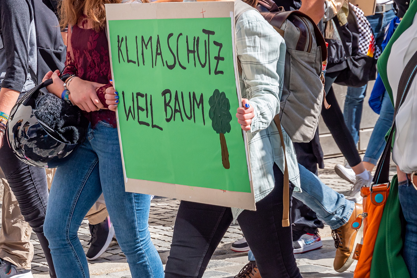 Demonstranten bei einer Demonstration für den Klimaschutz mit einem grünen Bild auf dem steht "Klimaschutz weil Baum"