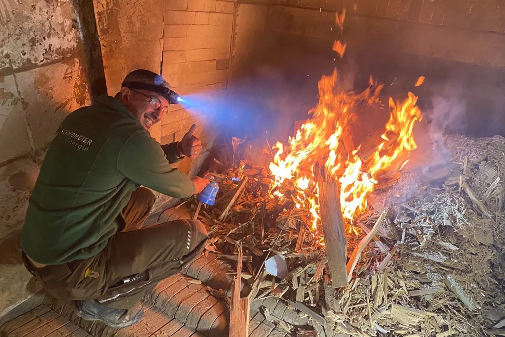 Mitarbeiter der Firma Schmidmeier NaturEnergie heizt Anlage in Kitzingen an