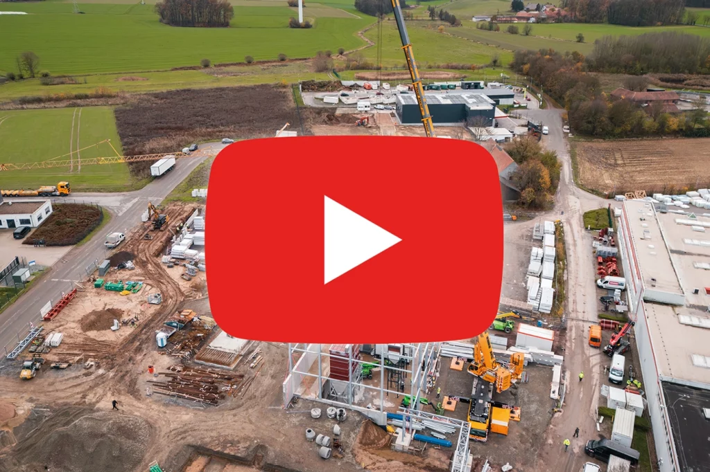 YouTube Logo ist ganz groß in der Mitte des Bildes. Im Hintergrund sieht man die Baustelle bei der Firma JET.