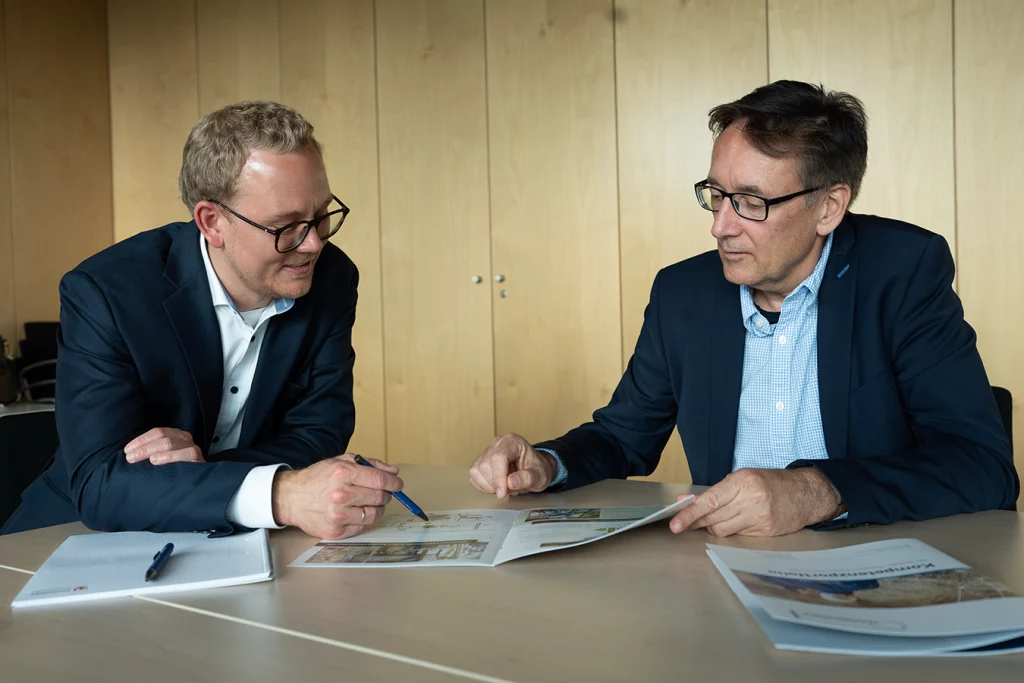 Ferdinand Schmidmeier und Pete Heuer diskutieren über einem Prospekt