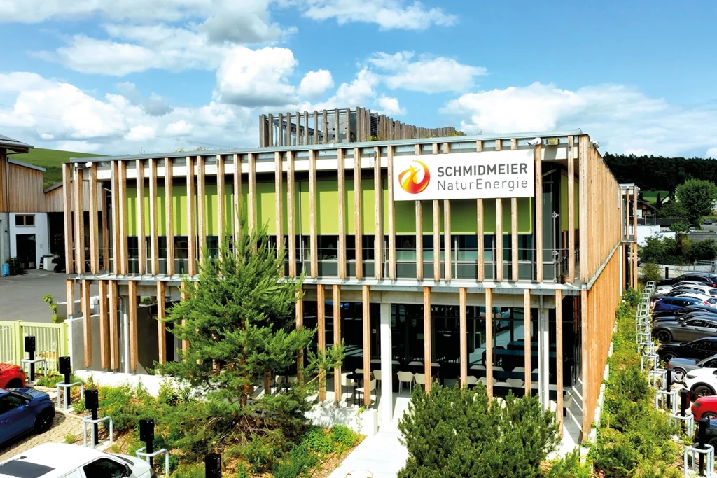 Verwaltungsgebäude der Schmidmeier NaturEnergie in Ödenthal. Die Außenfassade ist auf Holzbalken gestaltet. Das Logo der Firma befindet sich rechts in der Ecke.