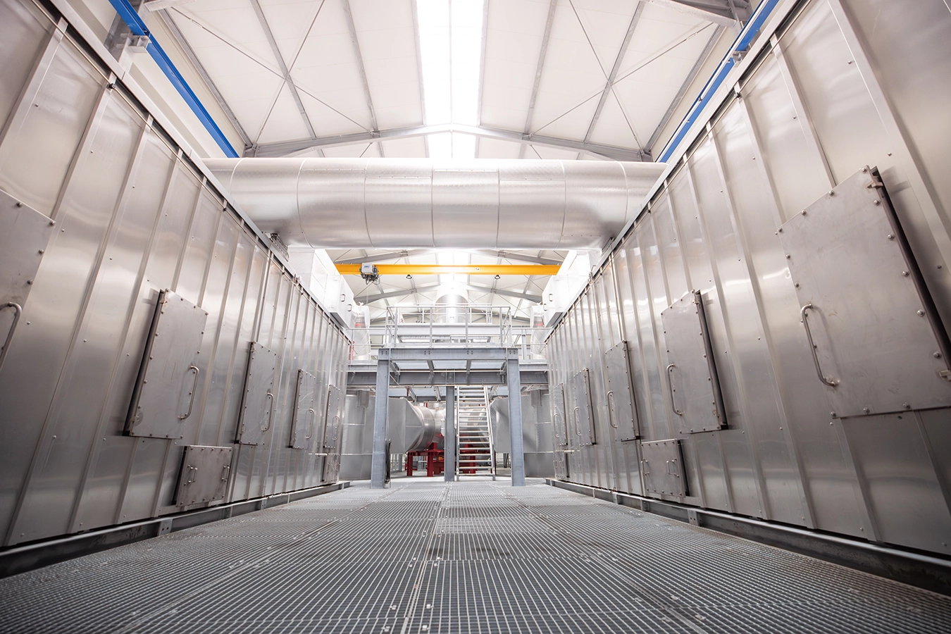 Biomasse-Heißgas-Anlage in Freihung von innen. Links und rechts befinden zwei gleiche Komponenten aus Metall, die in Längsrichtung mehrere kleine Türen besitzen. Diese liegen exakt gegenüber.