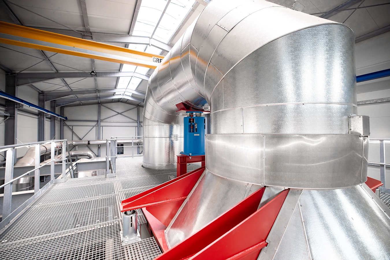 Biomasse-Heißgas-Anlage in Freihung von innen. Ein dickes rundes Rohr liegt wie die Form eines Griffs auf einer Ebene.