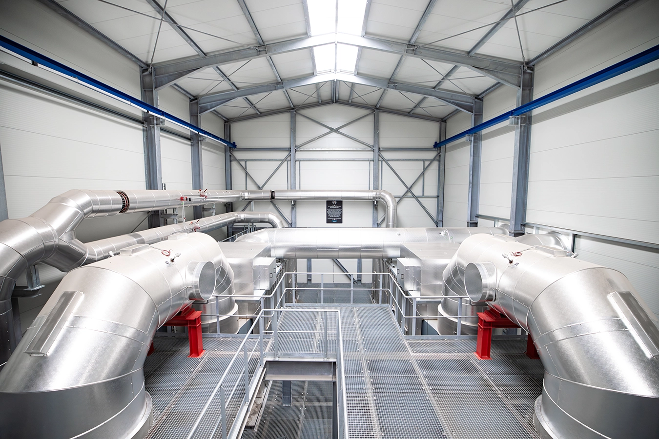 Biomasse-Heißgas-Anlage in Freihung von innen. Mehrere runde dicke Rohre liegen auf einer Ebene.