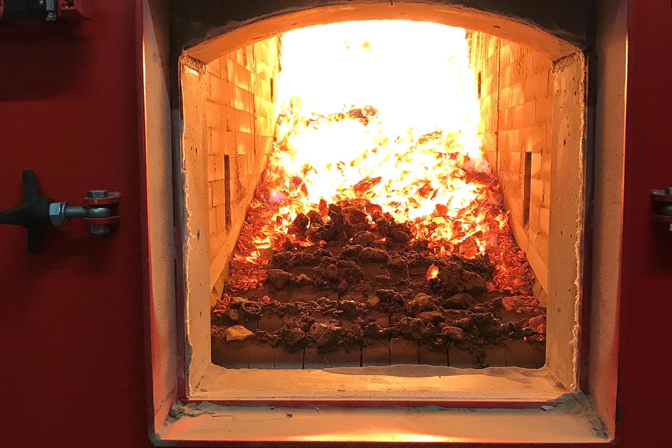 Im Feuerraum eines Biomasse-Warmwasserkessels brennt Feuer.