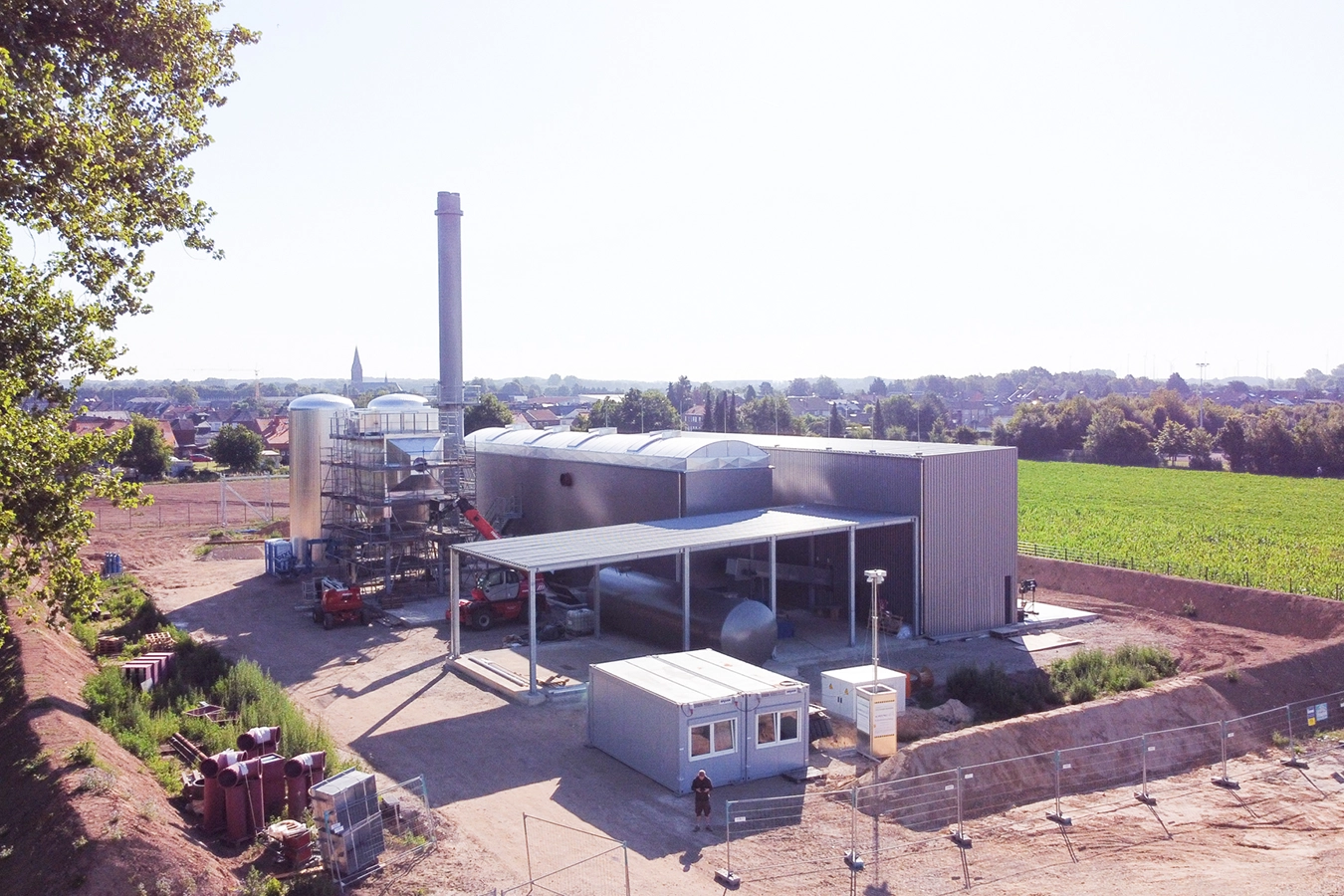 Baustelle eines Biomasse-Heizkraftwerks in Hückelhoven. Im Hintergrund liegen Häuser und ein Feld.