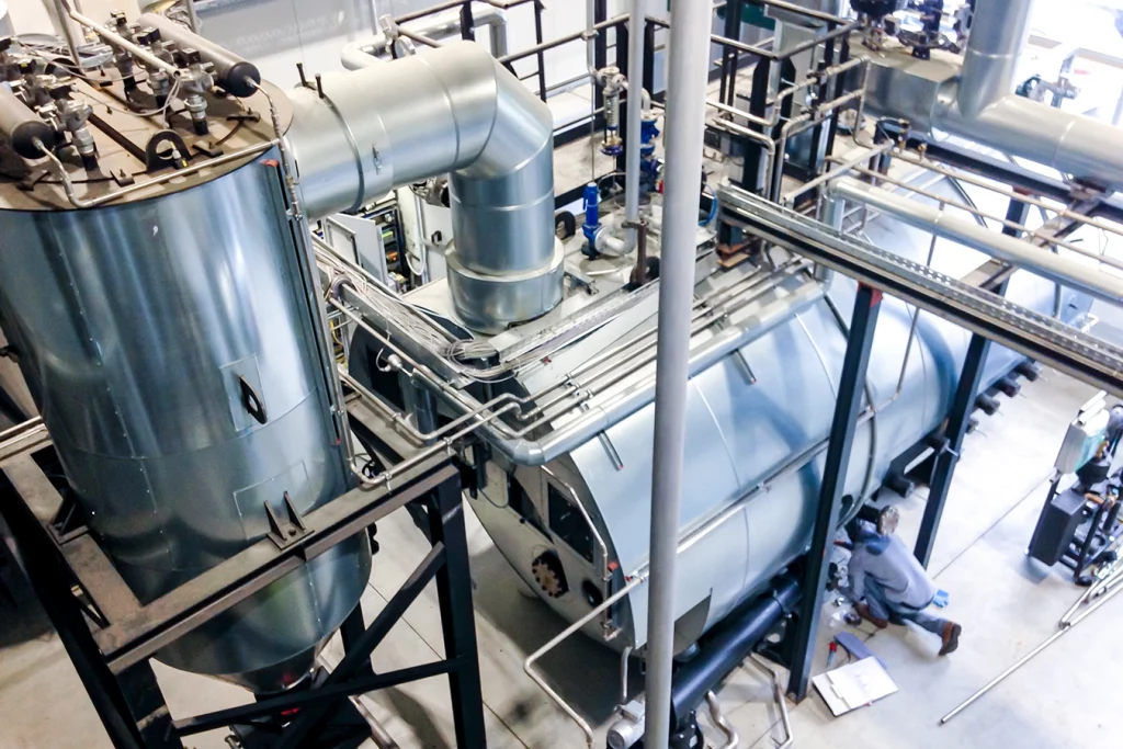 Technik einer biomassebefeuerten Prozessdampfanlage von innen. Rohre und Kessel aus Metall.
