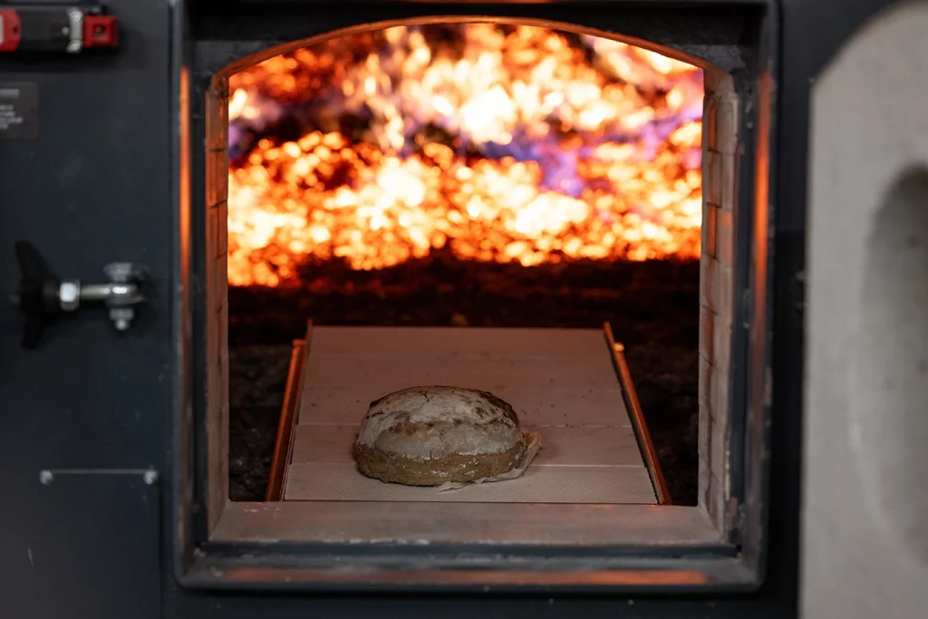Brot in einem Feuerraum, im Hintergrund brennt ein Feuer