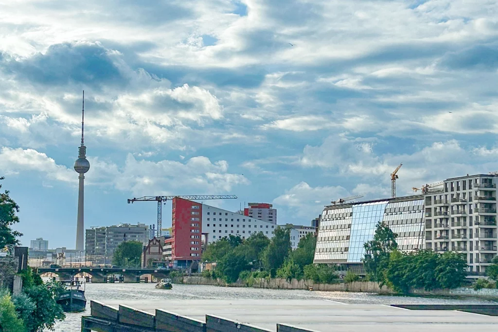 Die Spree und der Fernsehturm in Berlin ist zu erkennen. Das Bild ist aus der Perspektive einer Terrasse aufgenommen, die direkt an das Wasser der Spree anschließt.