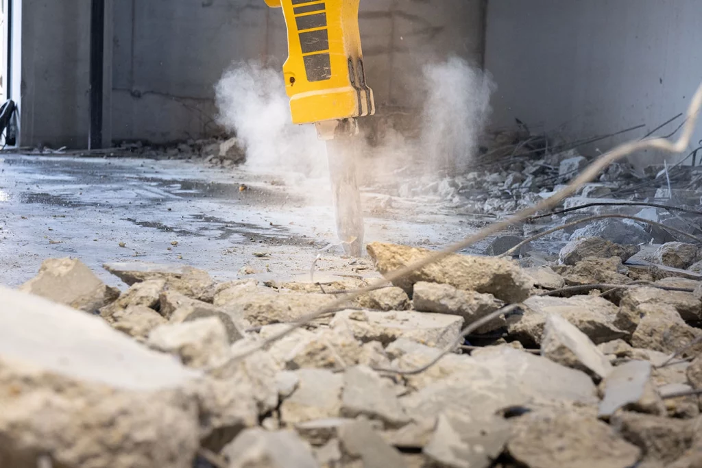Man sieht einen Bohrer in der Werkstatt. Rundherum liegen Steine am Boden.