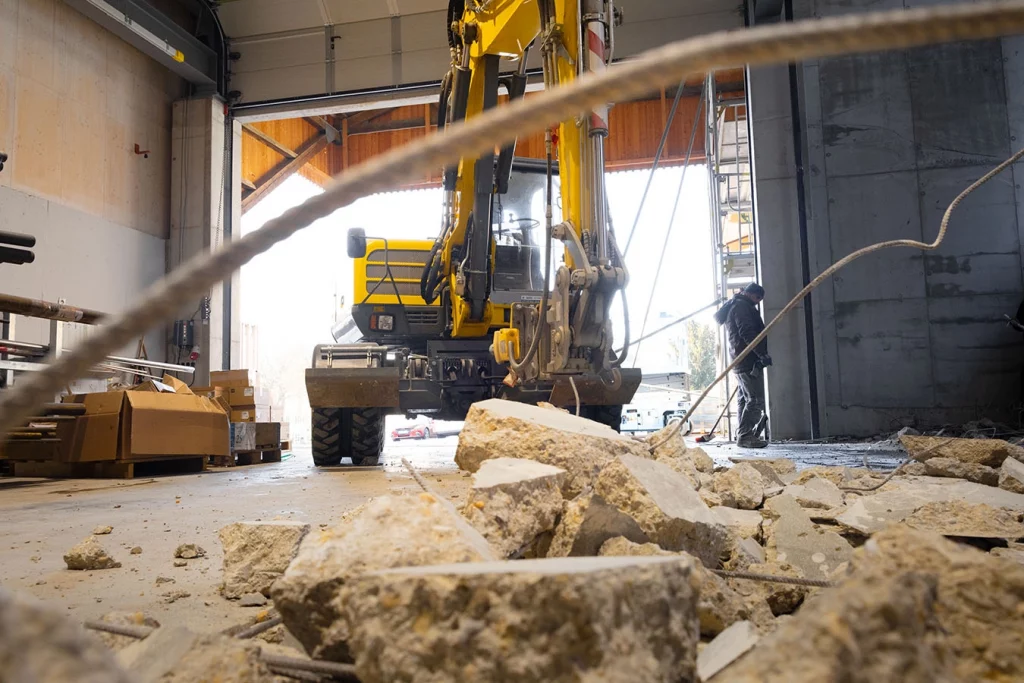 Man sieht einen gelben Bagger in der Werkstatt