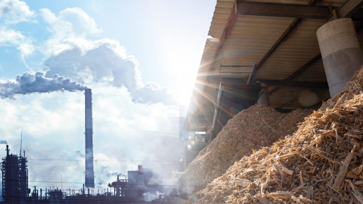 Symbolbild, links Schornsteine, rechts Holz in Brennstofflager