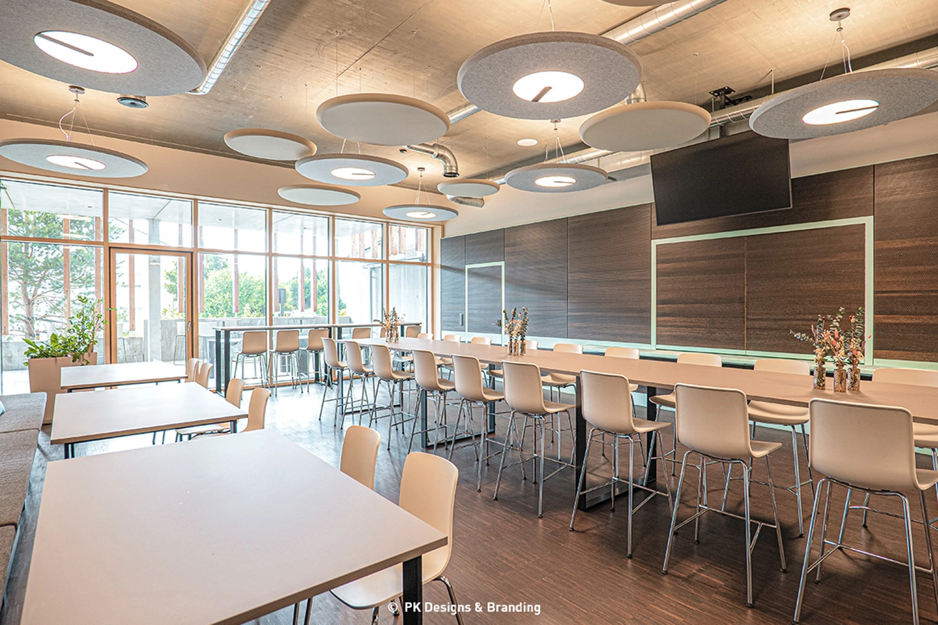 Das Bistro der Schmidmeier NaturEnergie, in der Mitte steht eine große, lange, hohe Tafel und Außenrum Tische. Es ist Platz für ca. 40 Personen