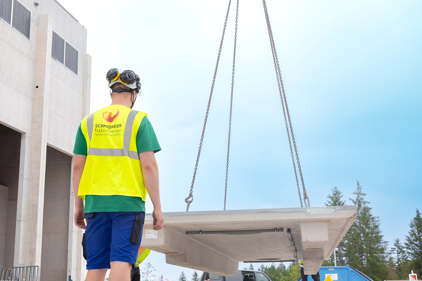 Mitarbeiter von Schmidmeier NaturEnergie geht auf eine Waage mit Baukomponenten zu