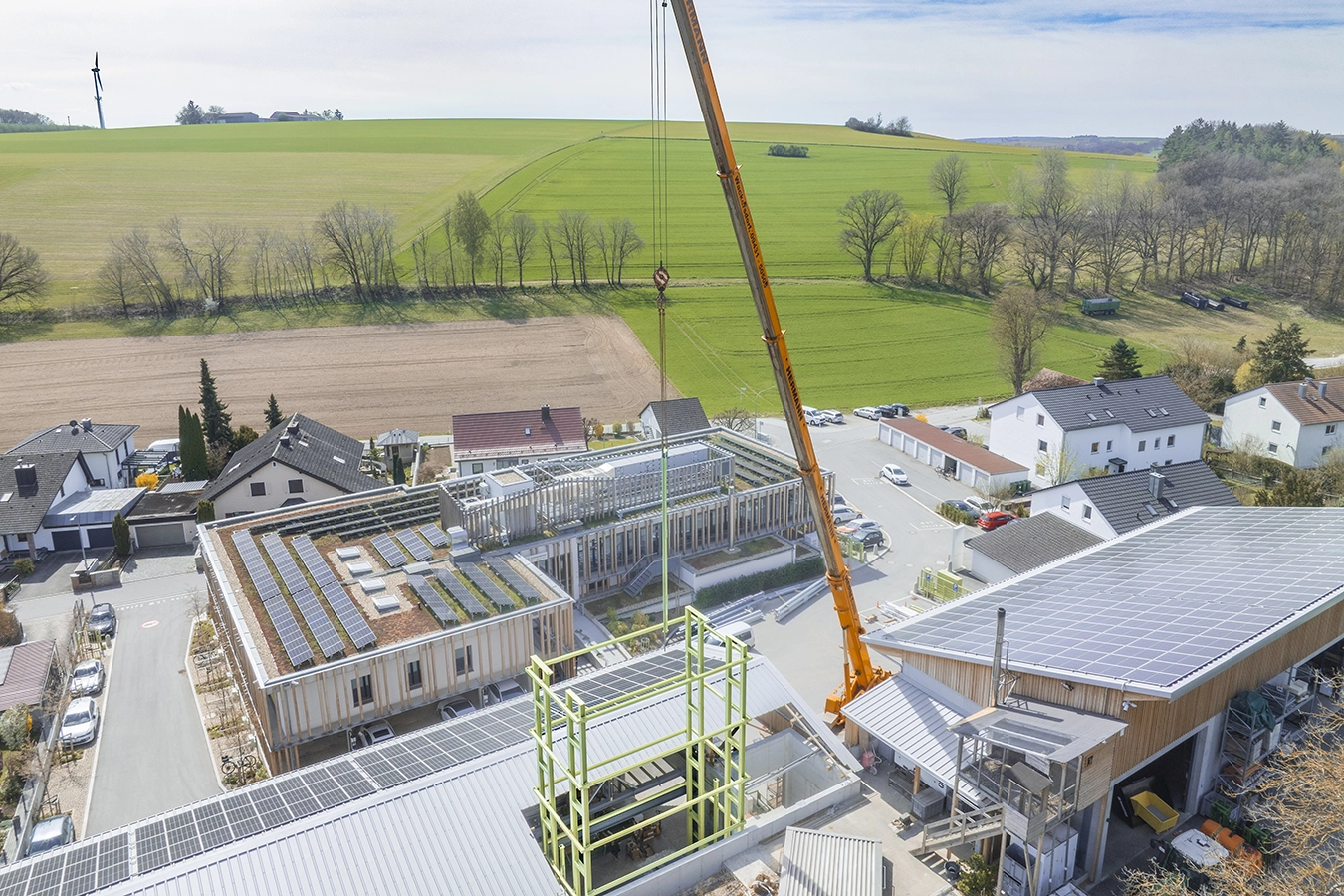 Drohnenaufnahme des Werkstattbaus in Zeitlarn. Kran setzt Stahlgerüst für die vollautomatisierten Lagersysteme ein