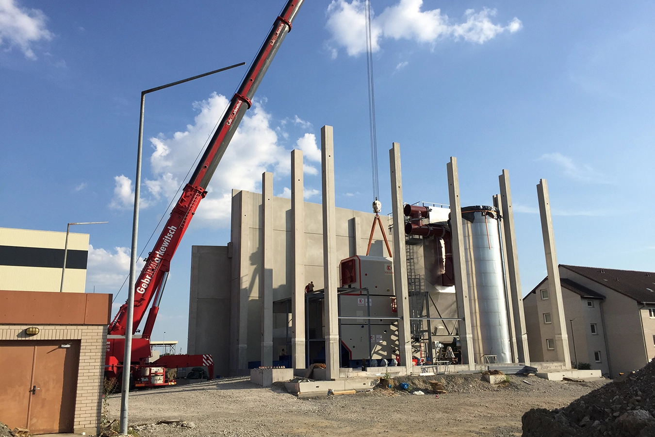 Laufender Bauprozess der Anlage in Kitzingen. Bau der Betongerüst mit noch offenen Dach und Wänden. Kran im trage Prozess.