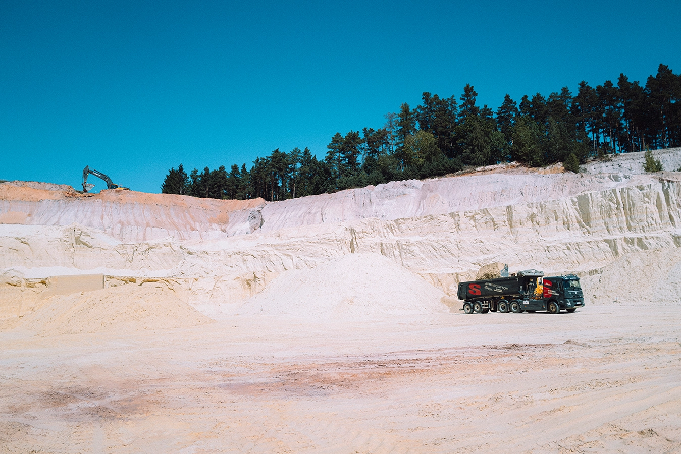LKW mit Strobel Quarzand Aufschrift wird mit Sand beladen.