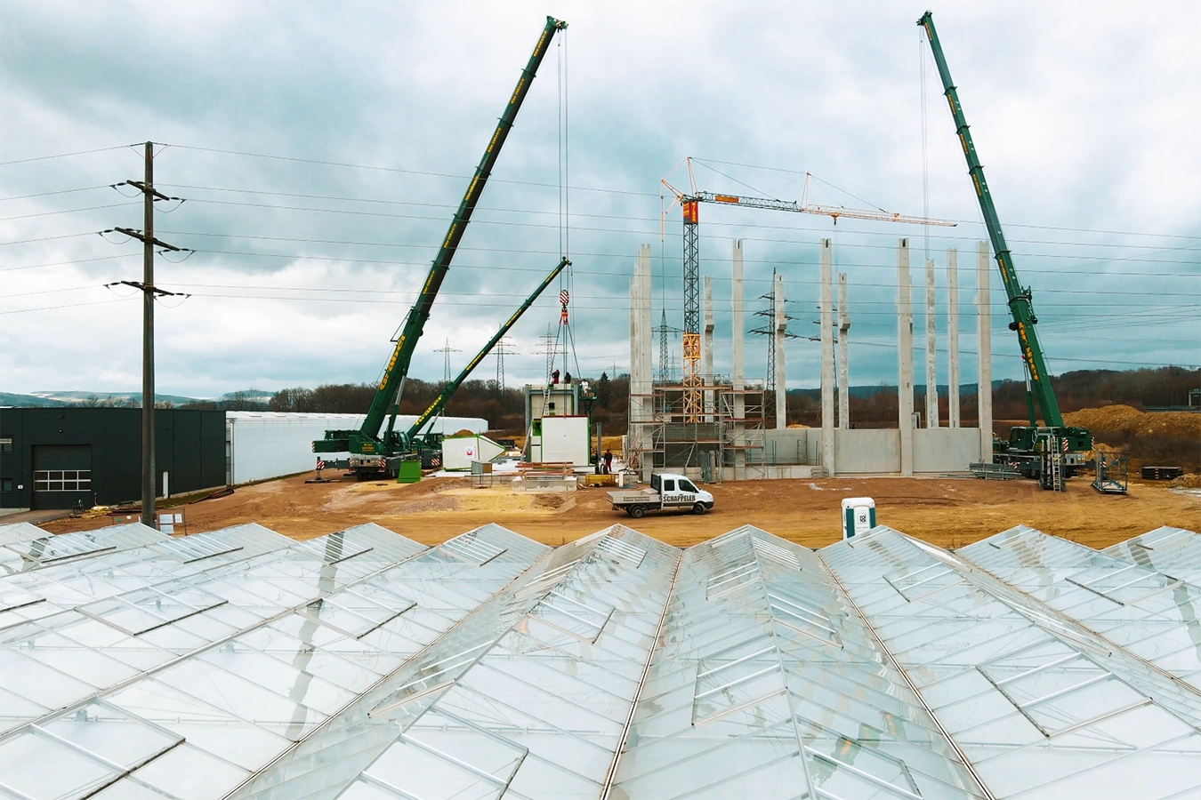 Laufender Bauprozess der Anlage in Singen. Mitarbeiter, Kran, Autos am Gelände.