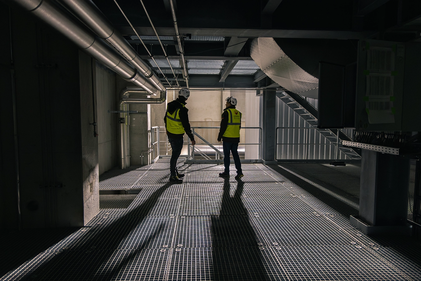 Zwei Mitarbeiter von Schmidmeier ausgerüstet mit Helm und Sicherheitskleidung in der Anlage von Avangard
