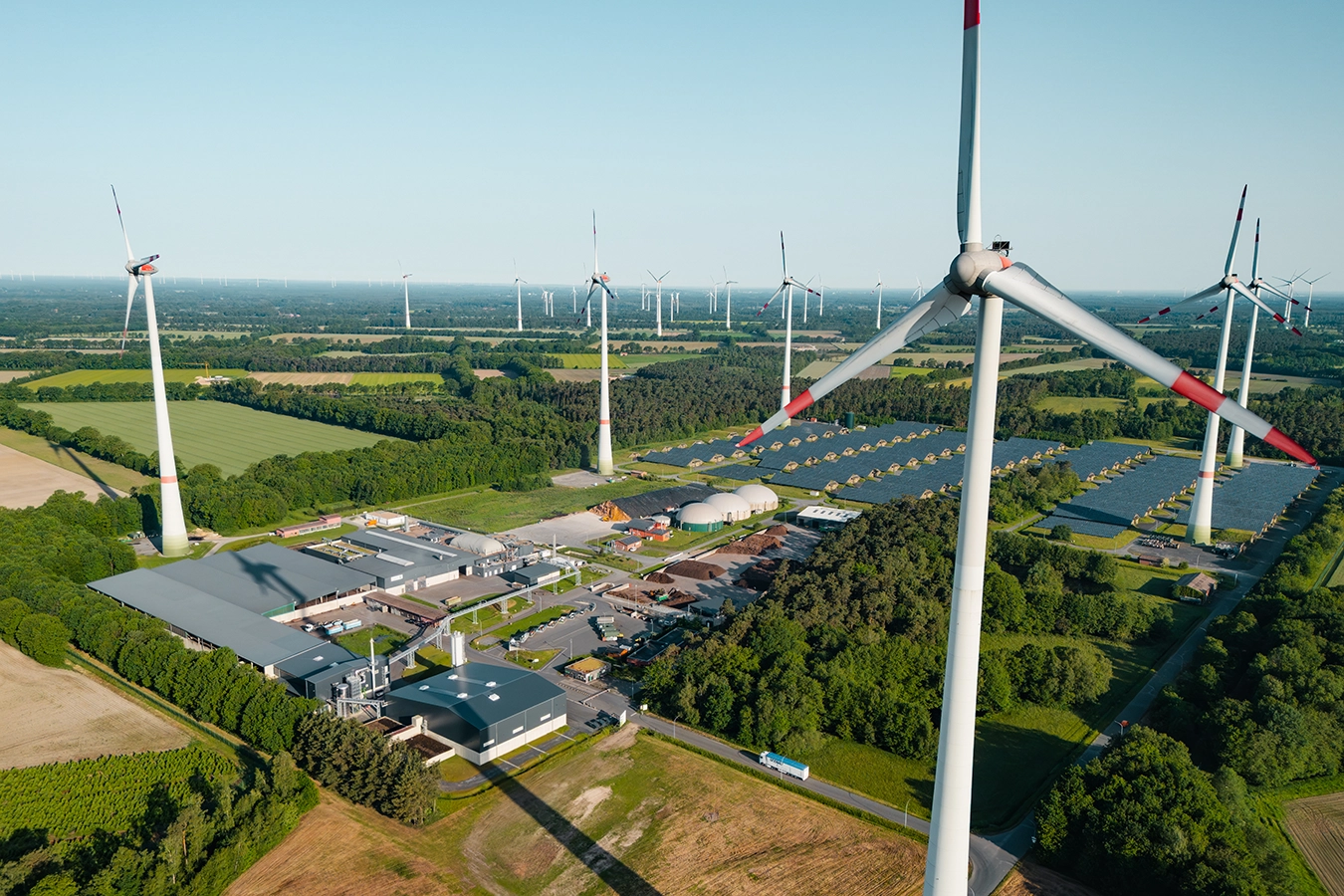 Eine Drohnenaufnahme zeigt Windräder und PV-Anlagen in Steinfurt während die Sonne im Hintergrund untergeht