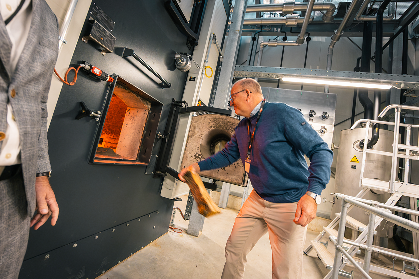 Dirk Brakemann (JET Formteile GmbH), wirft symbolisch Scheitholz in die Feuerung des Biomasse-Heizwerk der Schmidmeier NaturEnergie in Hüllhorst